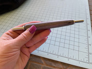 hand holding a sewing tool wth a seam ripper on one end and a stiletto in the other end 